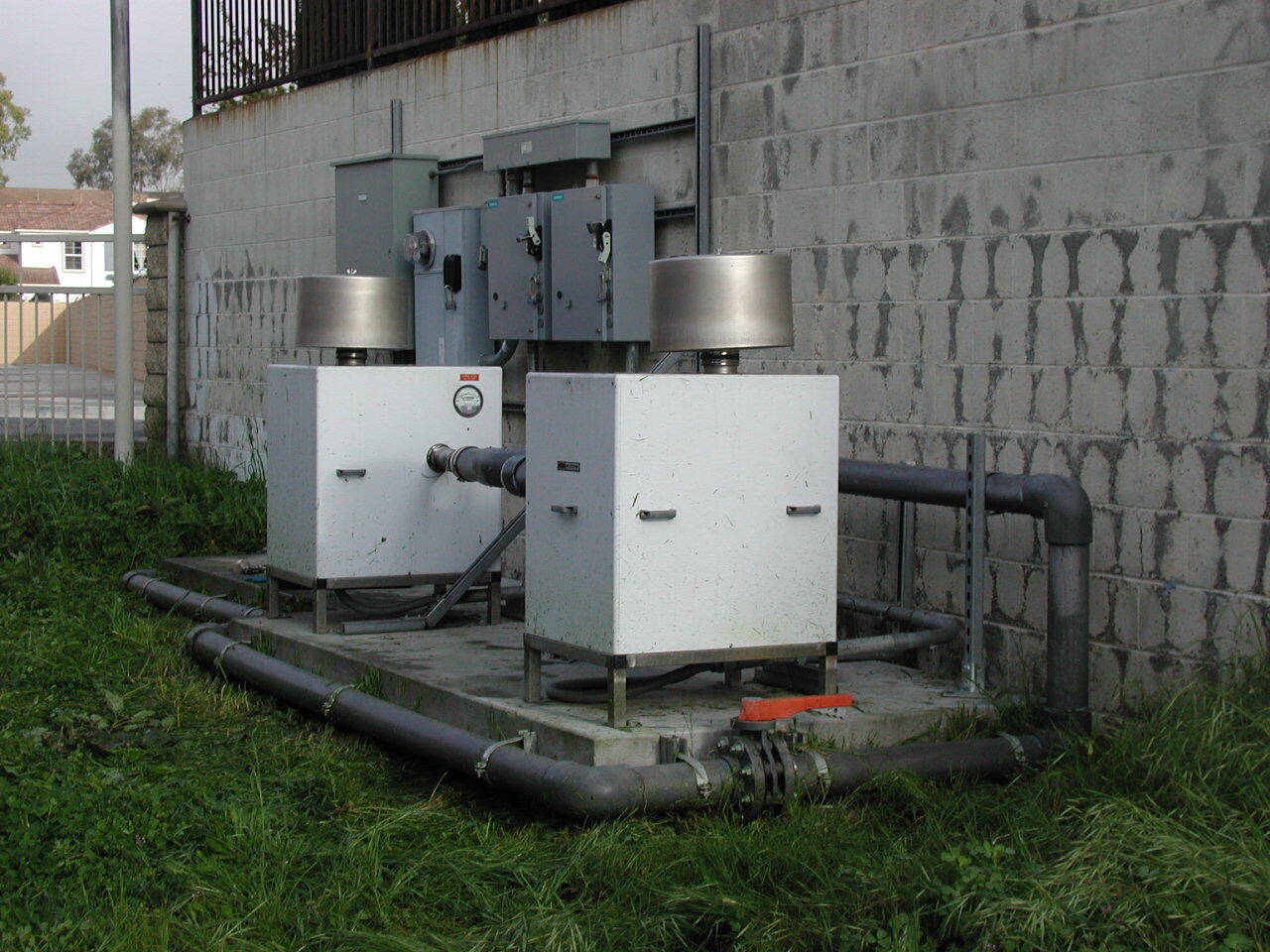 Two outdoor blower units with electrical controls and connected piping at a brownfield remediation site