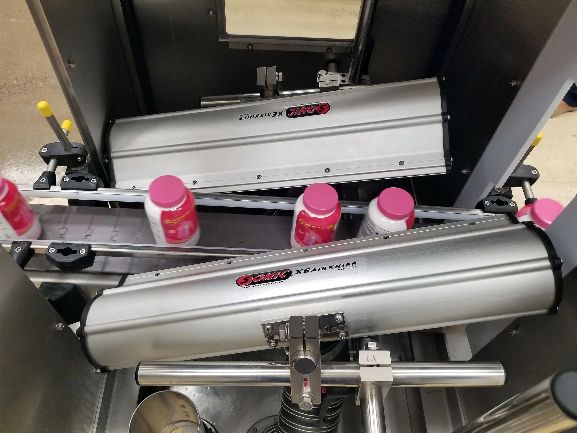 Industrial packaging machinery with bottles moving through a stainless-steel conveyor