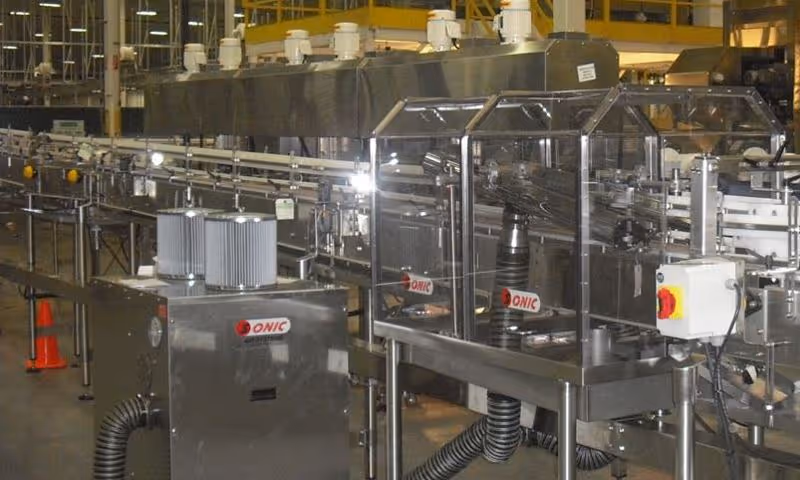 Sonic air knife tunnel installed over a bottling line conveyor