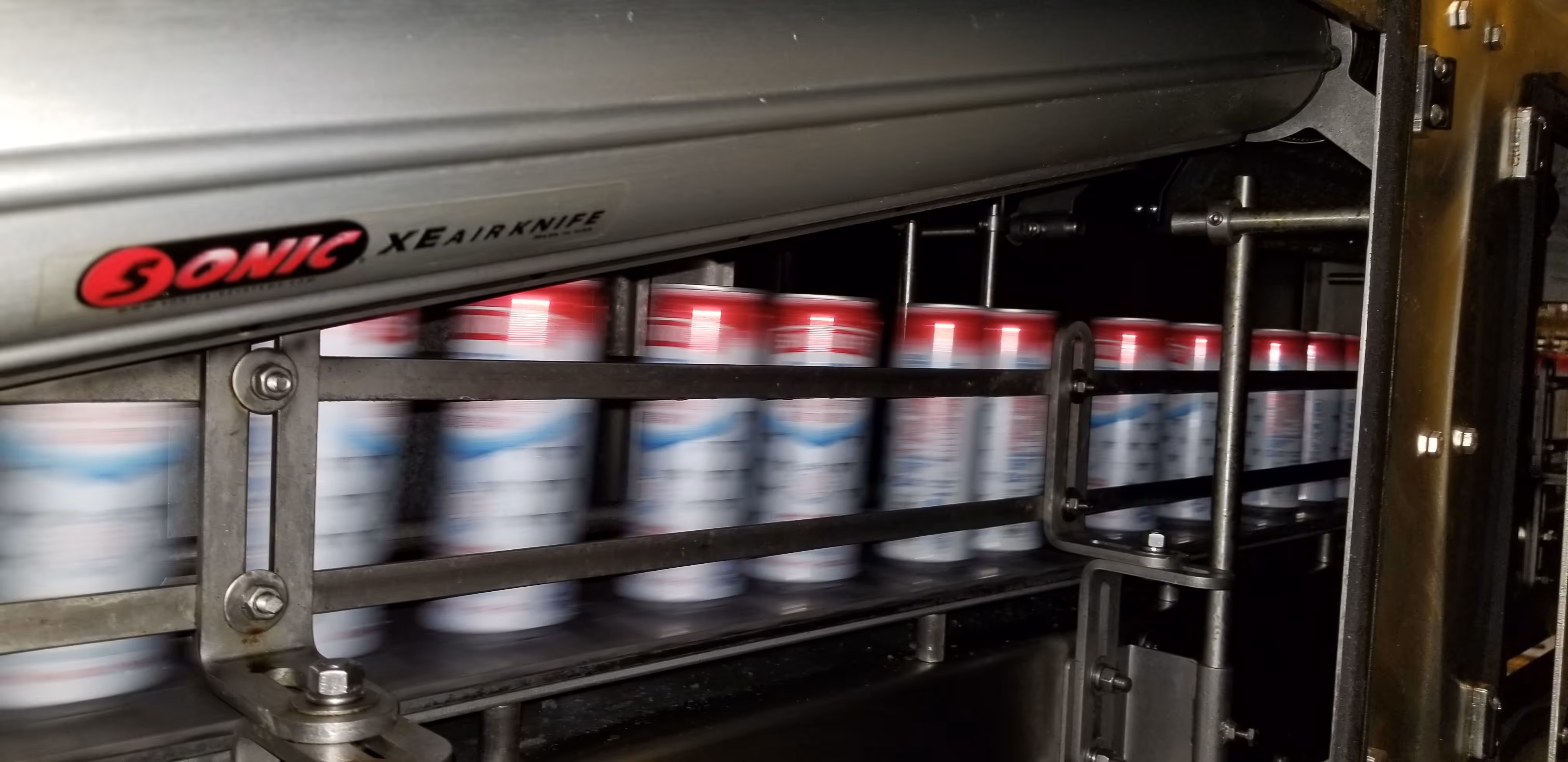 Sonic Air Systems high-speed air knife system drying beverage cans on a conveyor.